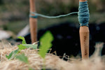 Pflanzleine mit "Wurzelwerk"-Logo und Schnurr gespannt im Beet im Detail